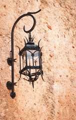 Black iron street lantern on a rough wall in Monaco.
