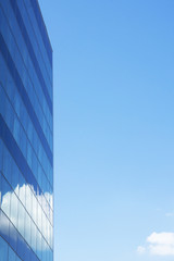 Blue building and sky with clouds. Glass on building reflect cloud and sky.