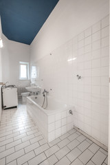 Fototapeta na wymiar old white tiled bathroom with bathtub - renovation concept