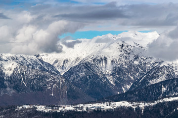 Obraz na płótnie Canvas The snow capped mountains are covered with thick clouds