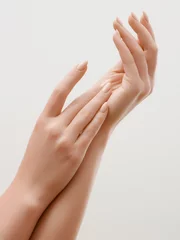 Fotobehang Closeup image of beautiful woman's hands with light pink manicure on the nails. Skin care for hands, manicure and beauty treatment. Elegant and graceful hands with slender graceful fingers © looking2thesky