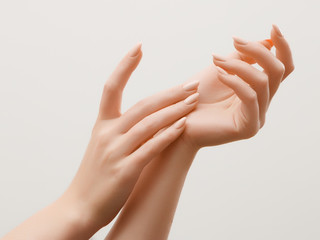 Close-upbeeld van de handen van de mooie vrouw met lichtroze manicure op de nagels. Huidverzorging voor handen, manicure en schoonheidsbehandeling. Elegante en sierlijke handen met slanke sierlijke vingers