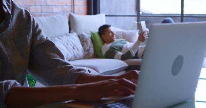 Woman using laptop while man reading book on sofa 4k