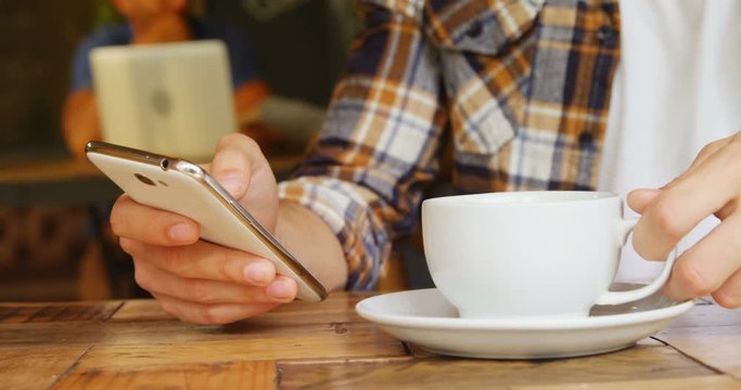 Man having coffee while using mobile phone in cafe 4k