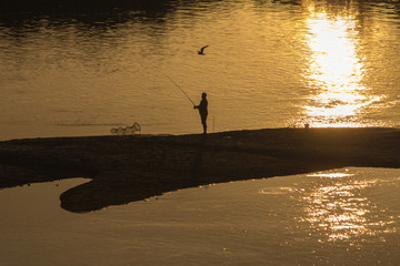 lonely fisherman at dawn on the river bank