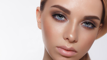 Fototapeta premium Glamour portrait of beautiful woman model with fresh daily makeup and romantic wavy hairstyle. Fashion shiny highlighter on skin, sexy gloss lips make-up and dark eyebrows