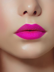 Fototapeta premium Close-up of woman's lips with bright fashion pink glossy makeup. Macro magenta lipgloss make-up. Sexy pink lip makeup. Highly saturated color. Lipstick