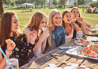 Group of happy girlfriends eating at the table together celebrating a birthday at the outdoor park.