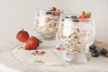 Healthy breakfast for two, oat meal with fruits: blueberry, strawberry and min, parfait in in two glasses on a rustic background. Healthy food. Isolated.