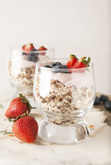 Healthy breakfast for two, oat meal with fruits: blueberry, strawberry and min, parfait in in two glasses on a rustic background. Healthy food. Isolated.