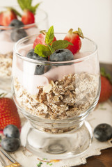 Healthy breakfast, oat meal with fruits: blueberry, strawberry and mint, parfait in a glass on dark wooden background. Healthy food. Isolated.