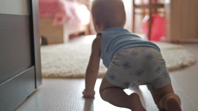 funny baby boy crawling on floor at home close-up of the baby's legs that creeps towards the toys on the floor