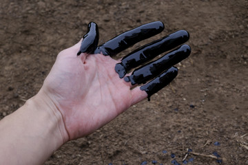 oil leaking. Very dirty hand.Stain hands showing thumbs up with black oil on soil background.