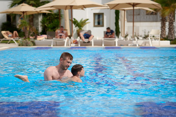 Father and son learning to swim in the swimming pool.