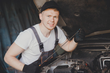 Obraz na płótnie Canvas Car mechanic working diagnostic equipment at automotive service. Checking oil level.