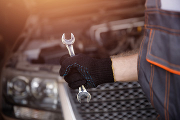 Wrench in hands of an auto repair garage mechanic service car.