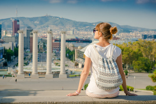 Girl tourist with a backpack looking at Barcelona. Girl sitting back and admiring the view of the city. Spain, walk around the city
