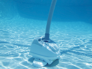 Underwater view of vacuum cleaning bottom of swimming pool.