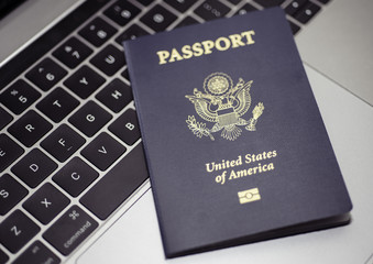 Passport of USA on Notebook's keyboard, close up. Blurred background.