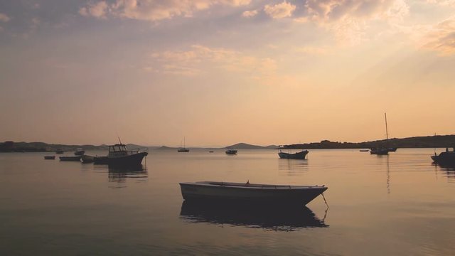 Small Transport Boats Hooked on Calm Sea at Sunset