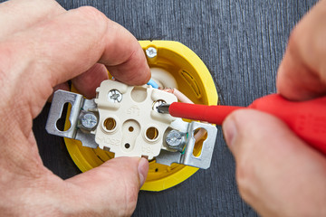 Installation of outlet in household electrical wiring, using cross-head screwdriver.