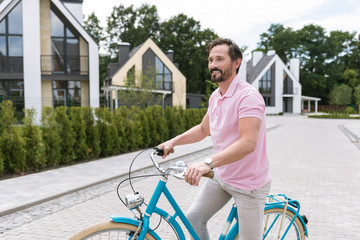 Favourite activity. Nice handsome man smiling while riding a bike