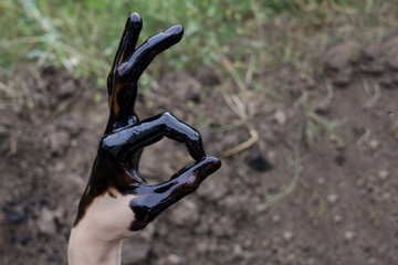 oil leaking. Very dirty hand.Stain hands showing thumbs up with black oil on soil background. hand showing OK