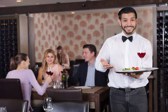 Waiter holding tray at restaurant with customers