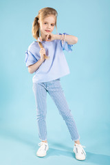 Full-length portrait of a beautiful girl in blue clothes on a blue background.