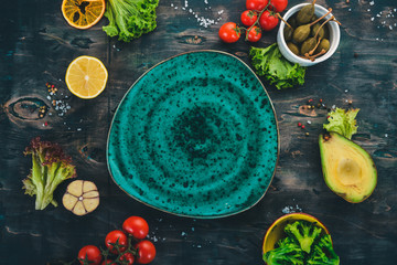 Green plate on a wooden background with vegetables. On a wooden table. Top view. Copy space.