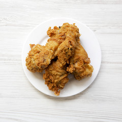 Fried chicken legs on a white round plate, top view. From above, overhead, flat lay.