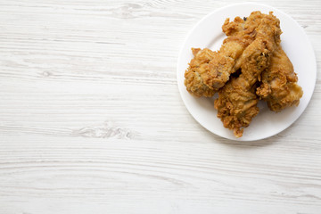 Fried chicken legs on a white round plate with copy space, overhead view. From above, top view, flat lay.