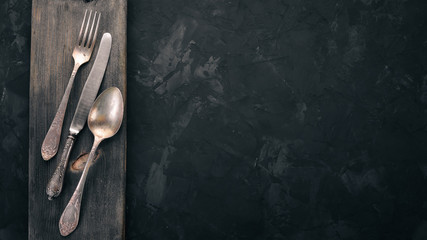 Old cutlery. On a black stone background. Top view. Free space for text. - obrazy, fototapety, plakaty