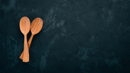 Wooden spoon On a black stone background. Top view. Free space for text.