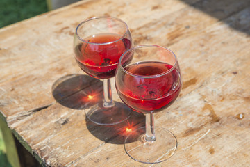 Two glass of pink wine with sunlight glare on old wooden table