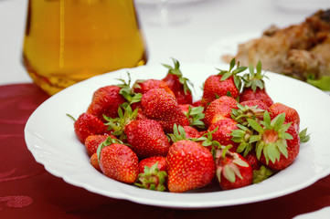 A red ripe strawberry lies on a plate.