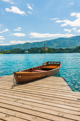 Harbor and boat on the Bled lake, Slovenia. Wooden boats on the pure blue water. Summer day near the Alps and forest