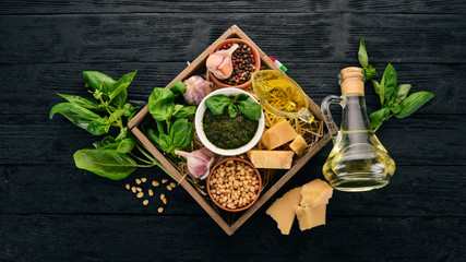 Ingredients for cooking Pesto sauce in a wooden box. Basil, parmesan cheese, olive oil, pine nuts, pepper, garlic. Top view.
