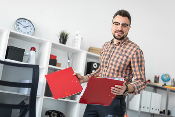 A man in the office pulls out the folders from the rack.