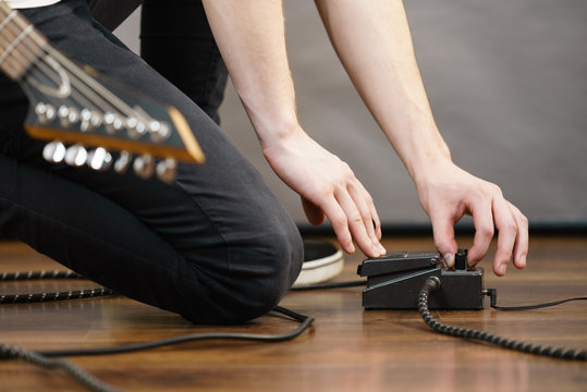 Man adjusting guitar effects pedal