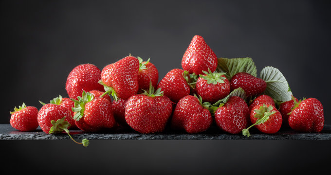 Ripe strawberries with green leaves on a black background.