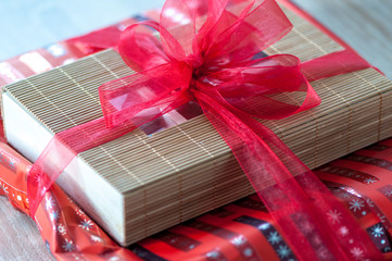 Close-up of a red bow gift wrapping around a box made of bamboo sticks