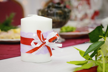 A decorated candle stands on the banquet table.