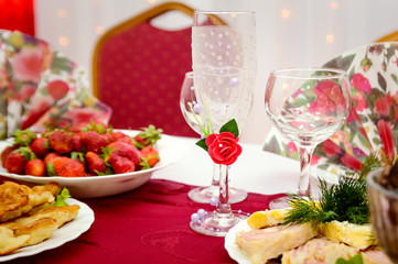 Empty decorative glass champagne glasses stand on the table. Fruits and snacks at a banquet. Festive table setting.