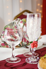 Empty decorative glass champagne glasses stand on the table. Festive table setting.