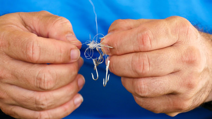 Man unraveling to the tangled and knotted Fishing line. Problem solving. - obrazy, fototapety, plakaty