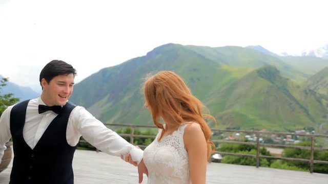 Merry newlyweds . Beautiful newlyweds in luxurious clothes spend a lot of fun in the background of the mountains