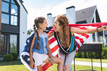 Obraz premium American patriots. Happy nice mother and daughter laughing while celebrating a holiday together