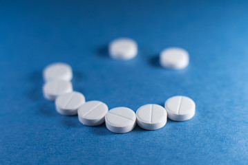 Happy smile made from white pills on blue background