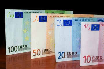 Close Up Euro Money Banknotes. cash Background. Money Bills With Reflection On The Table In Vertical Position. Finance And Economy Concept.